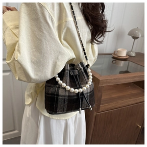 Detail of plaid bucket bag with pearl handle and metal chain shoulder strap