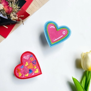 Phone socket grip with heart-shaped embroidery and colorful stitched patterns on white