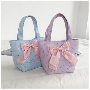 Close-up of star printed canvas tote bags with large pink satin bows in blue and purple
