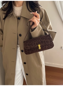 Close-up of leopard print shoulder bag with gold U-shaped buckle on a khaki trench coat