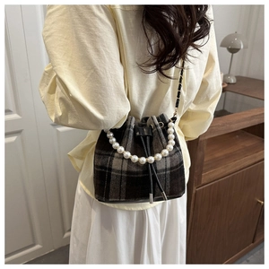 Macro detail of plaid bucket bag with pearl handle and leather drawstring closure