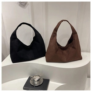 Detail view of large minimalist suede hobo bags in black and dark coffee on a display stand