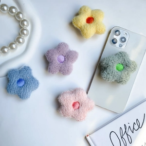 Macro shot of colorful plush star-shaped phone sockets on white desk with smartphone
