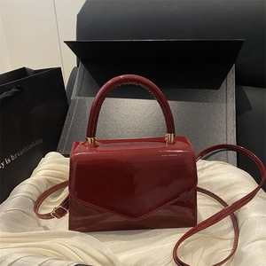 Glossy burgundy patent leather rectangular handbag with V-shaped flap and thin shoulder strap