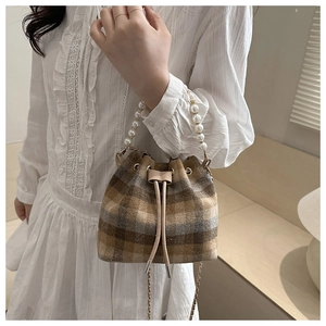 Detail of checkered bucket bag featuring a pearl handle and drawstring closure