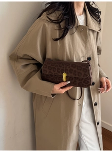 Detailed side view of leopard print baguette bag with golden buckle on female model