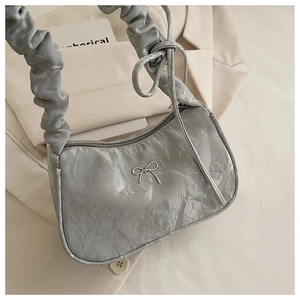 Detail of silver-grey hobo bag featuring pleated texture and metal bow decoration