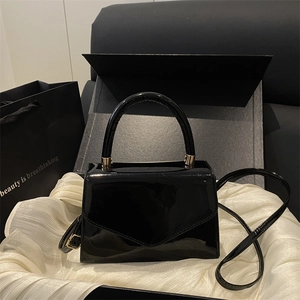 Minimalist black glossy patent leather crossbody handbag with golden metal handle accents