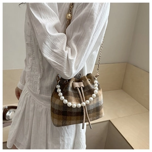 Detail of tweed checkered bucket bag with pearl handle and golden chain strap