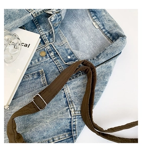 Detail of washed denim fabric with brown strap and adjustable gold metal buckle