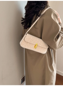 Close-up of beige leopard print underarm bag with gold oval buckle on a model