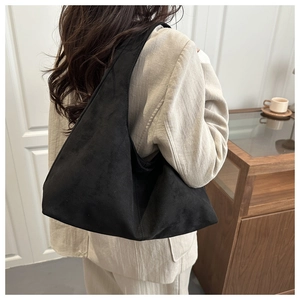 Close-up of black matte suede shoulder bag paired with beige linen blazer for a chic look