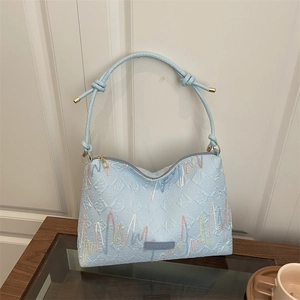 Light blue quilted shoulder bag with colorful wave embroidery and fashion label on front