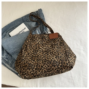 Detail of leopard print canvas tote bag with front pocket and silver metal rivet accents