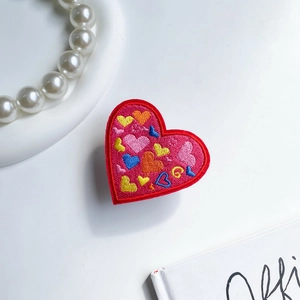 Close-up of red embroidered heart phone grip featuring colorful multi-tone heart patterns