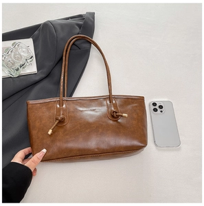 Gros plan sur un sac cabas marron vintage avec détail de nœud et logo embossé élégant