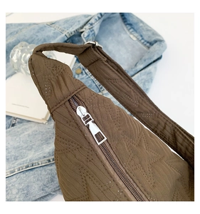 Detail of star-quilted brown crossbody bag fabric with smooth silver metal zipper