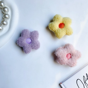 Detail of plush flower phone grips in purple, yellow and pink with embroidery