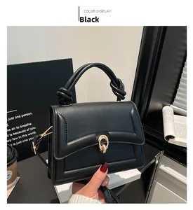 Detail of black handbag showing knot handle design and gold oval buckle close-up