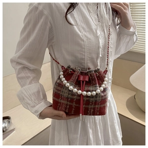 Detail of red-brown plaid bucket bag with pearl handle and metal chain shoulder strap