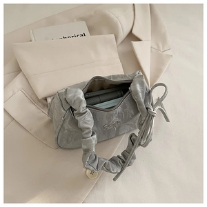 Detail view of grey ruched handbag with silver bow accent and zipper closure