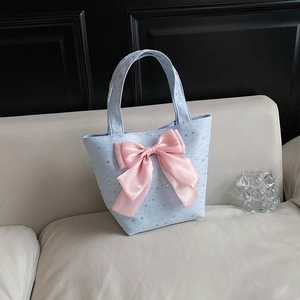 Large casual tote bag with star pattern and oversized pink bow on a grey sofa