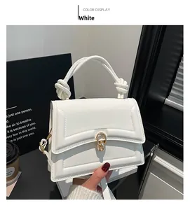 Detail of white PU leather crossbody bag with gold lock and braided handle knot