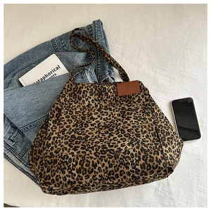 Detailed view of leopard print canvas tote bag with front pocket on textured white fabric