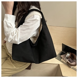 Close-up of minimalist black suede shoulder bag worn by model in a cozy lifestyle setting