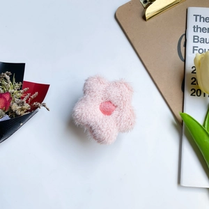 Macro view of a soft pink plush flower phone stand with fluffy texture and central detail