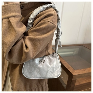Details der silbernen metallischen Plissee-Achseltasche mit Struktur und Schleifenverzierung