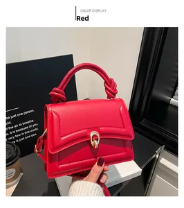 Close-up of red quilted hand bag with gold lock and unique knotted handle detail