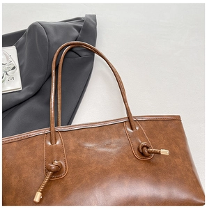 Détail du sac cabas marron foncé avec cordons noués et finitions métalliques dorées