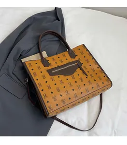 Detail of caramel tote bag with cartoon bear pattern and brown leather straps