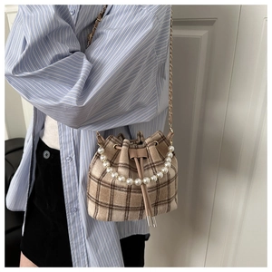 Fashionable plaid bucket bag detail with white pearl handle and gold chain strap