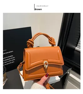 Detail of a brown leather handbag with unique knotted handle and gold metal ring lock