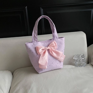 Lavender tote bag with silver star pattern and large pink satin bow on a sofa