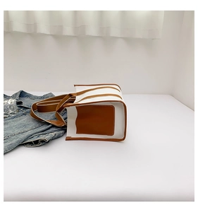 Detail of canvas tote bag with brown leather trim and reinforced base stitching