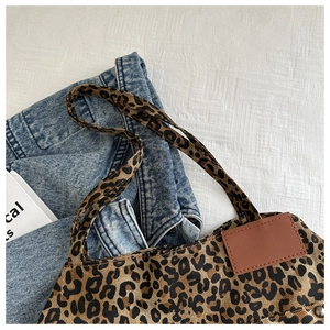 Detail of leopard print canvas tote bag with brown leather tag and sturdy bottom rivets