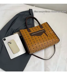 Detail view of brown bear tote bag size compared to a phone and tablet on bed