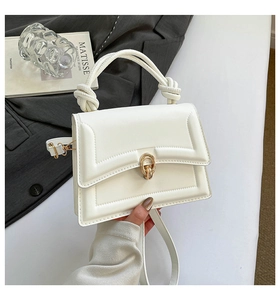 Dettaglio della borsa in pelle PU bianca con chiusura a scatto dorata e manico intrecciato