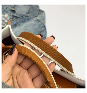 Detail of woven brown shoulder strap with beige stripes on stylish canvas tote bag