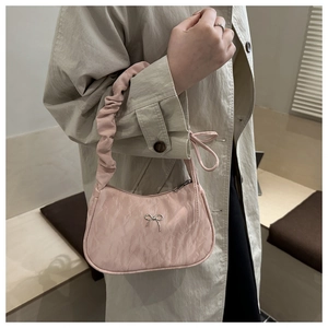 Detailed view of pink pleated handbag with silver bow detail and ruffled handle