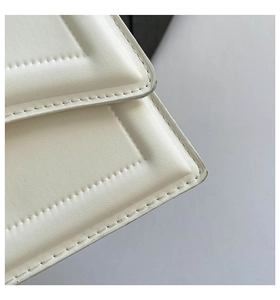 Vista macro delle cuciture raffinate e della trama in pelle premium sulla borsa bianca