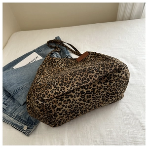 Macro detail of leopard print canvas tote bag featuring brown leather side label