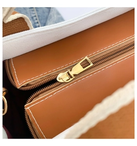 Detailed close-up of brown leather and white canvas stitching with gold zipper and metal hardware