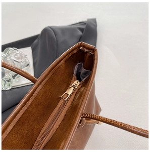 Détail du zip doré sur un sac cabas en cuir marron montrant la finition de qualité