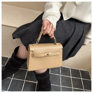Detail of elegant beige leather handbag with classic gold clasp on textured surface