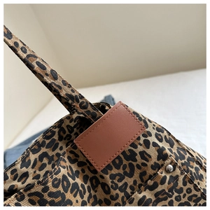 Close-up of leopard print canvas tote with brown leather patch and rivet detail