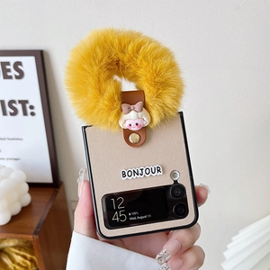 Detail of beige leather Galaxy Z Flip case with a large yellow plush ring and girl pendant